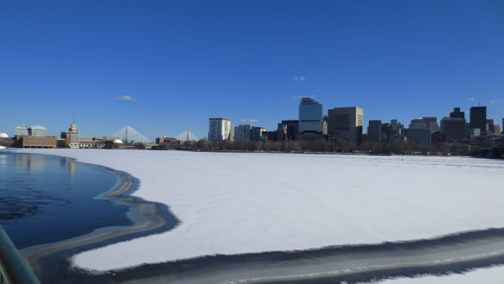 澄み切った真っ青な空と、中高層の建物、白く凍ったチャールズ川